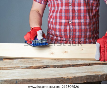 Polishing wooden pine board with the sandpaper