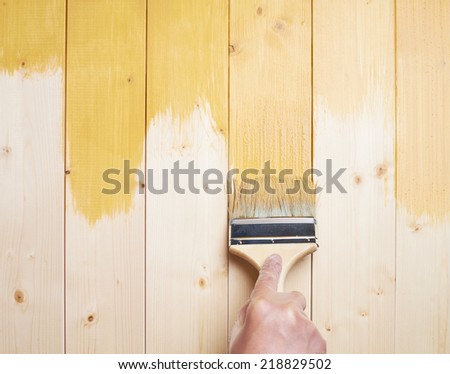 Process of painting the pine wood boards with the brush and the yellow paint