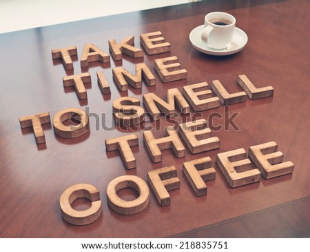 Take time to smell coffee quote made with the block wooden letters over the table, next to a cup of coffee, composition with tone image correction