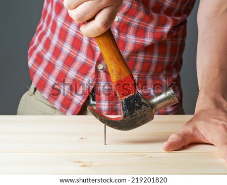 Taking out the nail from the wooden boards with the help of the hammer tool composition
