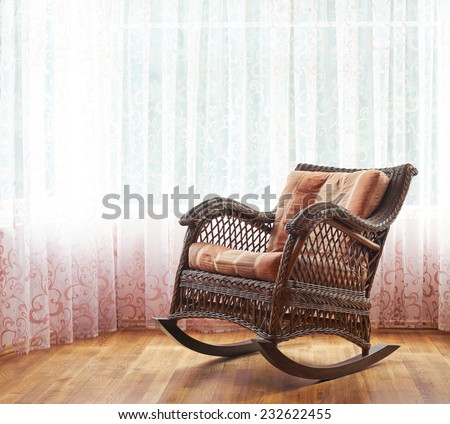 Brown wicker rocking chair against the window\'s curtains, indoor composition