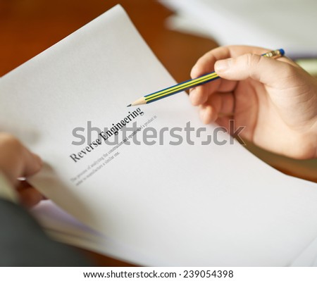 Reverse Engineering definition as a shallow depth of field close-up composition of a man in a business suit working with the text