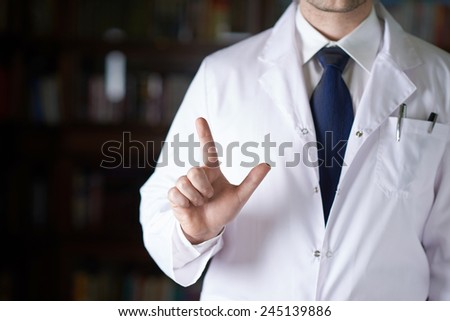 Close-up fragment of a man in a white doctor\'s coat holding a pointing finger in front of him, shallow depth of field composition