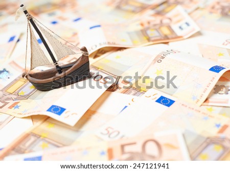 Tiny ship over the surface covered with the multiple fifty euro bank notes
