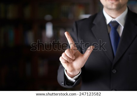 Close-up fragment of a man in a business suit pointing to something with a finger, shallow depth of field composition