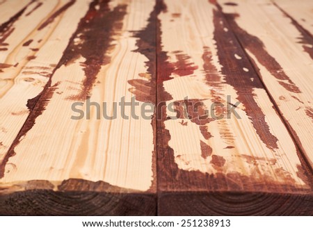 Surface covered with multiple pine wood boards with the paint stains and leaks in the gaps, as an abstract background composition with a shallow depth of field