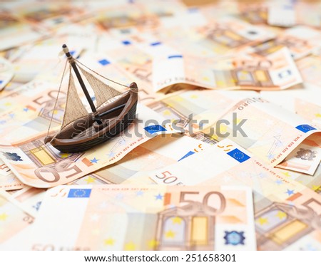 Tiny ship over the surface covered with the multiple fifty euro bank notes
