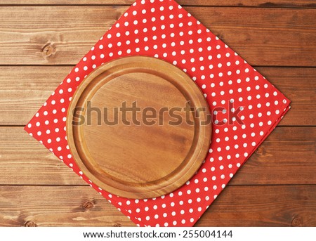 Red polka dot tablecloth or towel over the surface of a brown wooden table with a round wooden tray on top of it