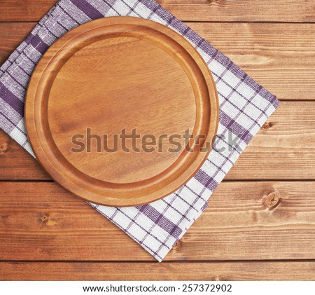 Violet tablecloth or towel over the surface of a brown wooden table with a round wooden tray on top of it