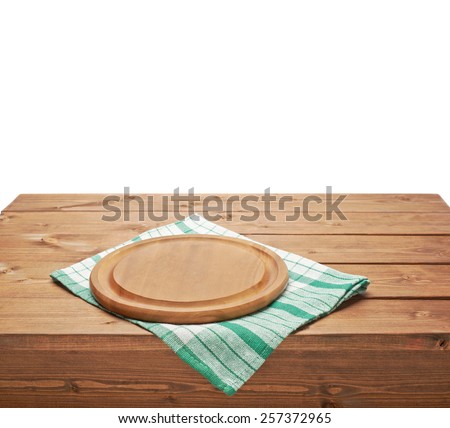 Green tablecloth or towel over the surface of a brown wooden table with a round wooden tray on top of it, composition isolated over the white background