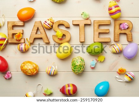 Word Easter made of wooden letters and surrounded with multiple egg decorations as a festive Easter background composition