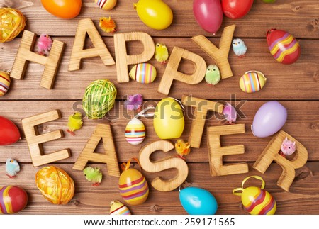 Words Happy Easter made of wooden letters and surrounded with multiple egg decorations as a festive Easter background composition