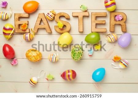 Word Easter made of wooden letters and surrounded with multiple egg decorations as a festive Easter background composition