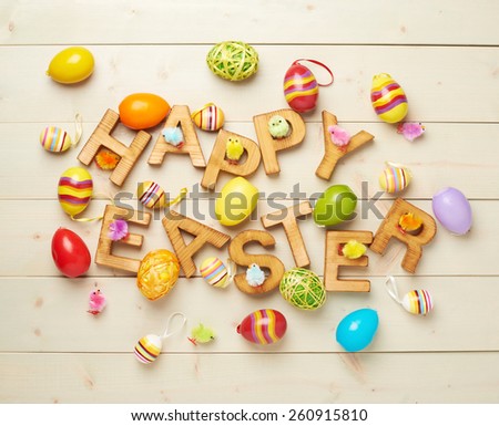 Words Happy Easter made of wooden letters and surrounded with multiple egg decorations as a festive Easter background composition