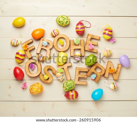 Words Frohe Ostern as Happy Easter in german language made of wooden letters and surrounded with multiple egg decorations as a festive Easter background composition