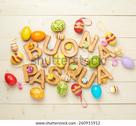 Words Buona Pasqua as Happy Easter in italian language made of wooden letters and surrounded with multiple egg decorations as a festive Easter background composition