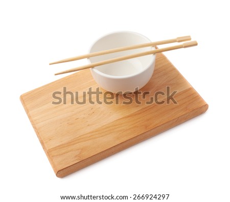 Chinese dinner composition of the white ceramic bowl and wooden chopsticks over the small wooden board isolated over the white background