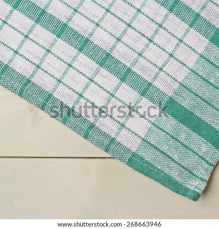 Green squared tablecloth or towel over the surface of a wooden table