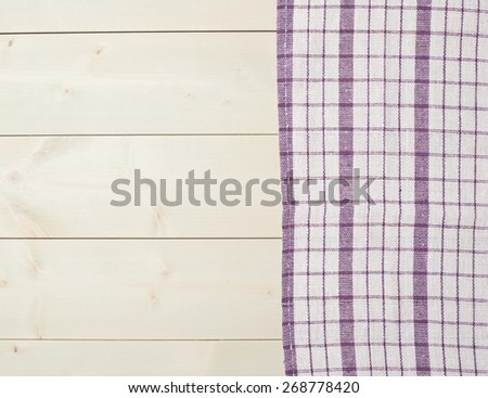 Violet squared tablecloth or towel over the surface of a wooden table
