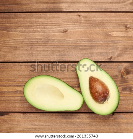 Avocado fruit lying over the brown colored wooden board surface as a background composition