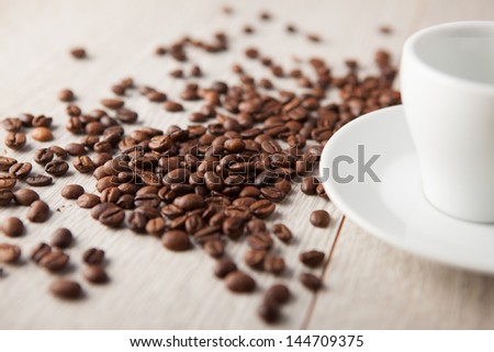 coffee cup with coffee beans scattered on a wooden board