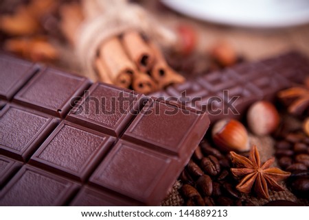 bar of chocolate with cinnamon and coffee beans on a burlap background