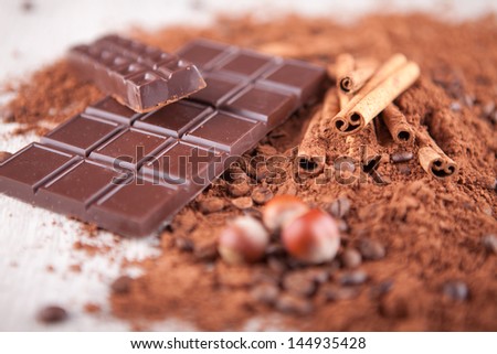 cocoa powder, chocolate bars and nuts o n a wooden board