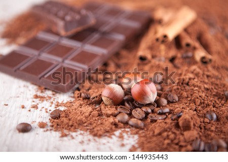 cocoa powder, chocolate bars and nuts o n a wooden board