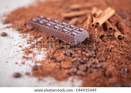 cocoa powder, chocolate bars and nuts on a wooden background