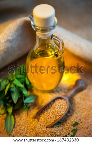 mustard oil in a vessel with seeds on a wooden background