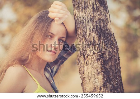 Sad Trendy Hipster Girl Relaxing on the road near tree at the day time. Concept of Modern Youth Lifestyle .