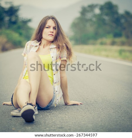 Trendy Hipster Girl Relaxing on the road at the day time. Concept of Modern Youth Lifestyle.