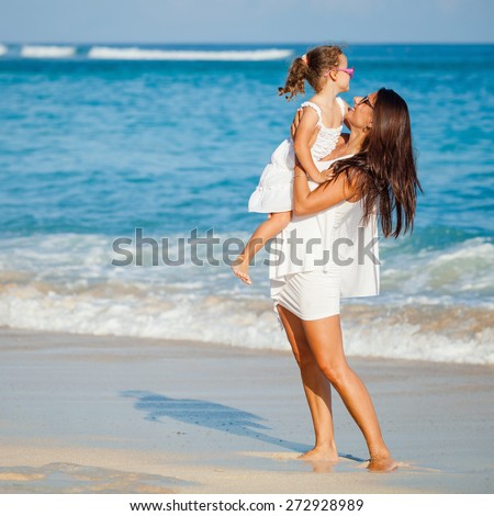 Mother and daughter playing on the beach at the day time. Concept of friendly family.