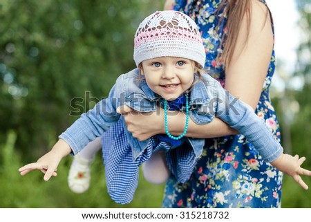 Mother and little daughter playing at the park at the day time. Concept of friendly family.