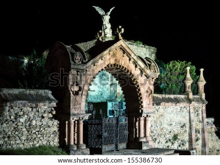 entrance to a gothic cemetery by night with an angel statue