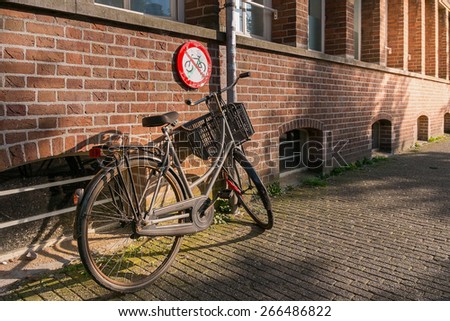 A bicycle parked under a no parking signal
