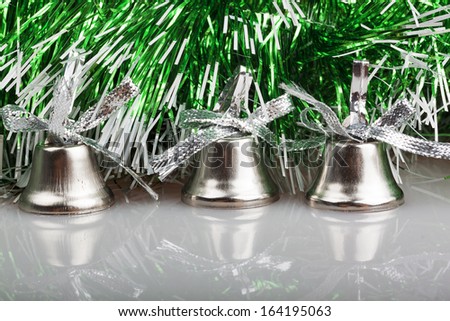 three silver bells on the background of green garland