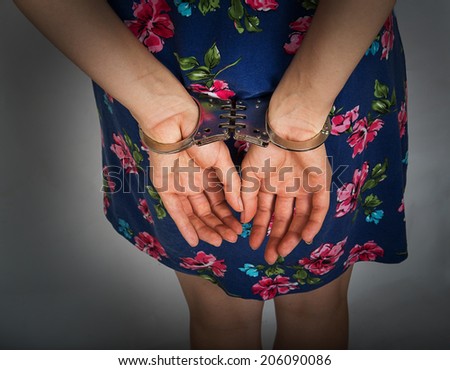 Female hands in handcuffs on a gray background