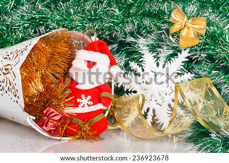 Santa Claus with white bucket, red gift box and white snowflake on a background of green garland