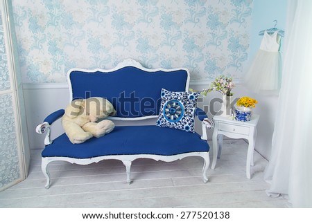 Blue classical style sofa couch with white teddy bear in vintage room