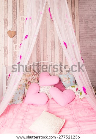 Four-poster bed with pink pillows in the studio