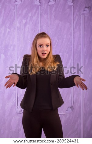 Portrait of a surprised young woman in a black suit on a purple background