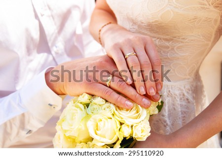 Hands and rings on wedding bouquet close up