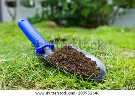 ground in the small shovel on the green grass,garden tool for planting