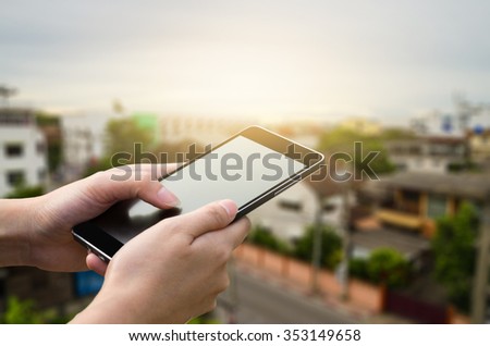 woman hand hold and touch smart phone,cell phone,mobile over blurred image of city scape  in Thailand,business connection concept
