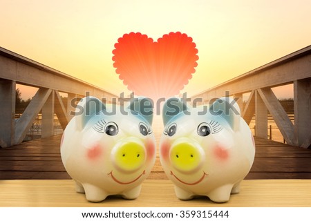 piggy bank couple on wooden ground enjoy and happy in love over red heart on wooden bridge,valentine day concept