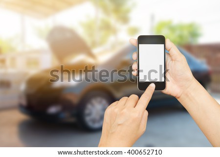 woman hand holding,using and touch smart phone,cell phone,mobile over blurred image of broken black car : concept calling mechanic service from repair shop