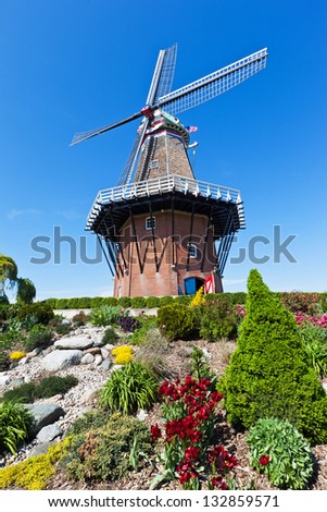 An authentic wooden windmill from the Netherlands stands among tulips and other vegetation on Windmill Island in Holland Michigan during their springtime tulip festival