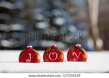 Christmas ornaments sitting in snow that spell JOY with room for text above