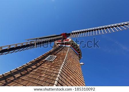 Authentic Dutch wooden windmill in Holland Michigan. Close up of blades and cedar shake shingles with window. Sky is the backdrop
